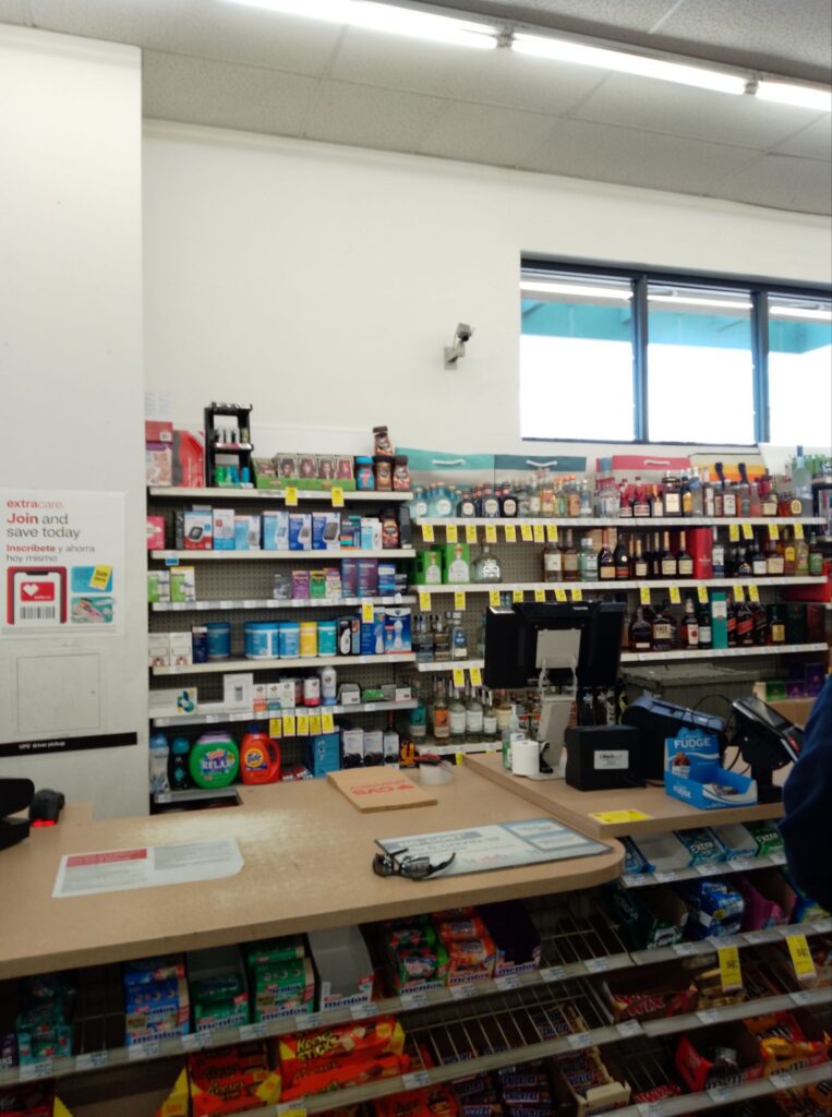 Picture of a drugstore counter, with medical supplies  next to a shelf of hard liquors.